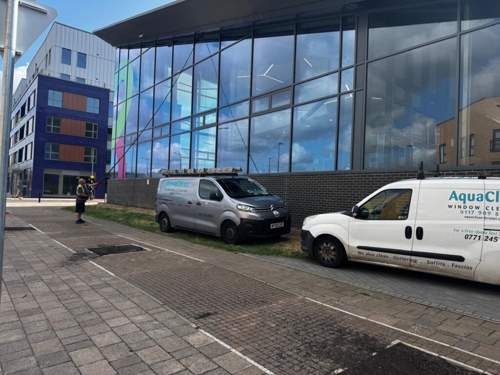 AquaClean vans and operative alongside a large glazed building frontage