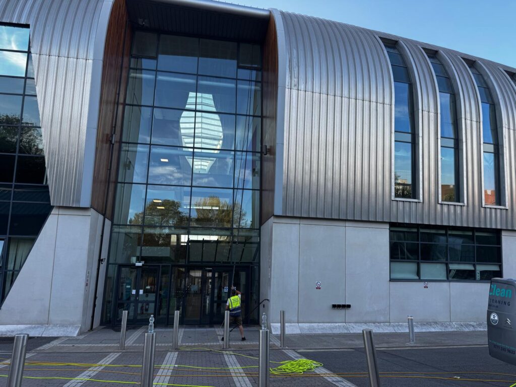 AquaClean operative cleaning a tall glazed entrance from ground level
