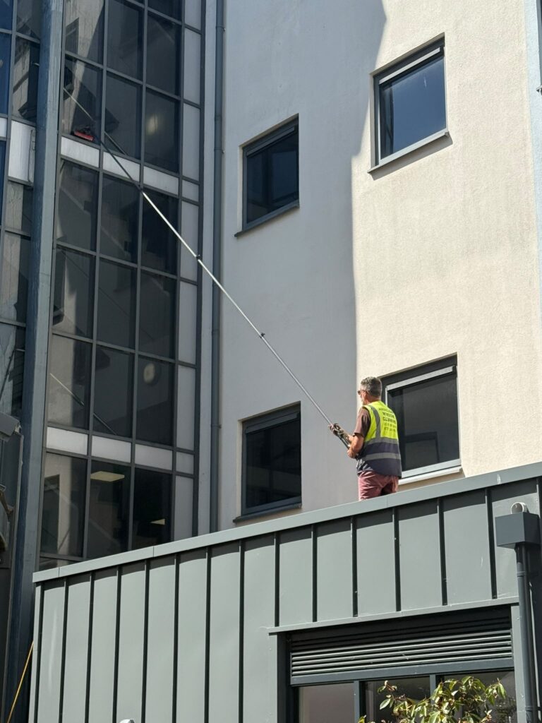 AquaClean operative extending a cleaning pole towards tall glazing
