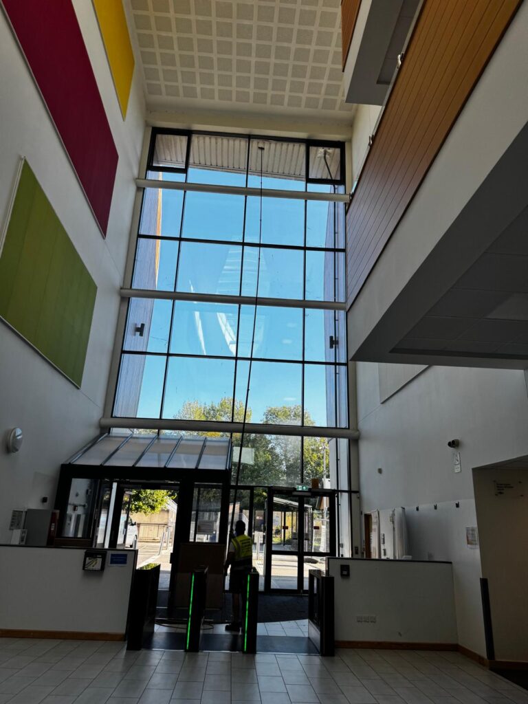AquaClean operative using a long pole at interior entrance glazing